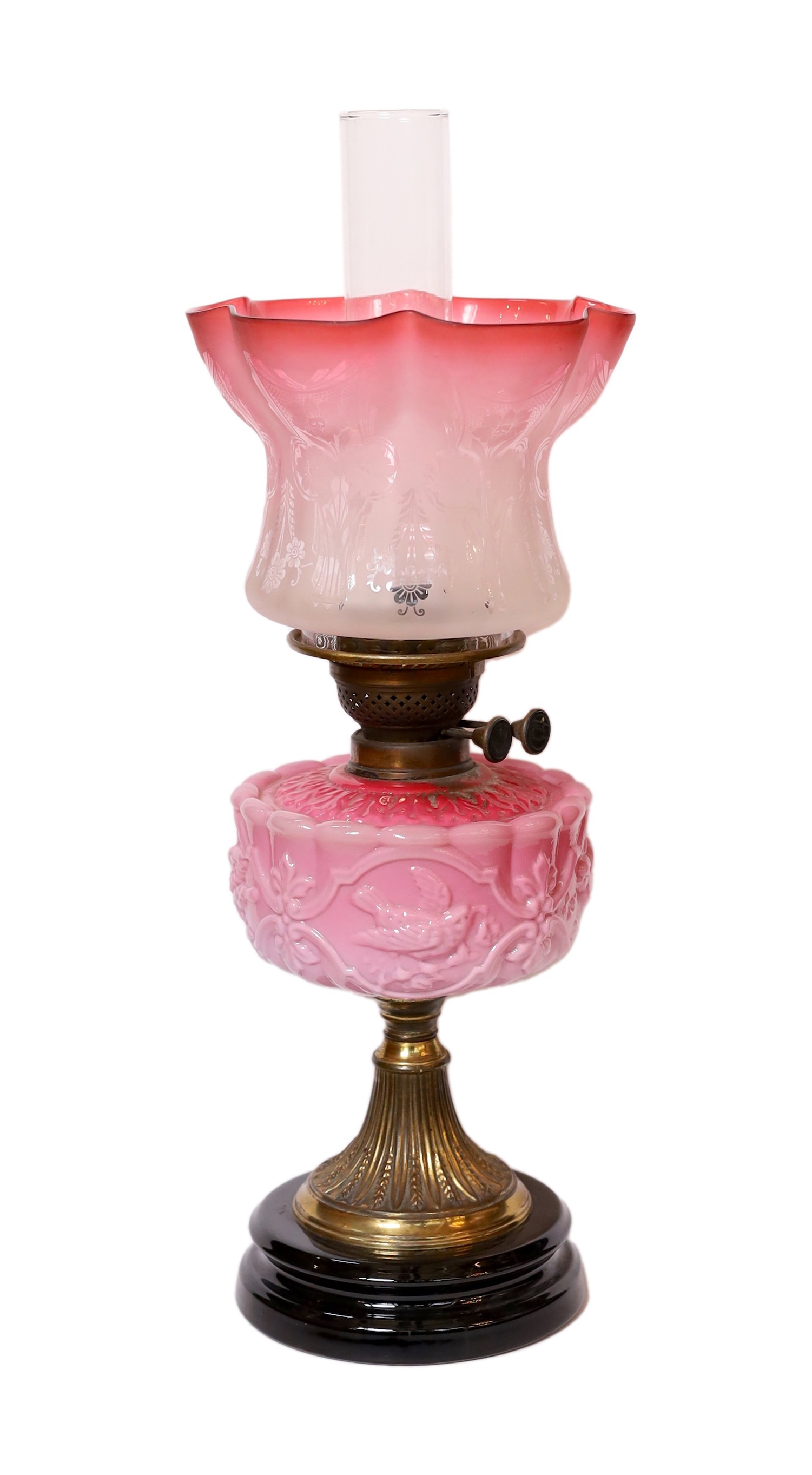 A late Victorian brass and pink opaque glass oil lamp with tinted frosted shade, height overall