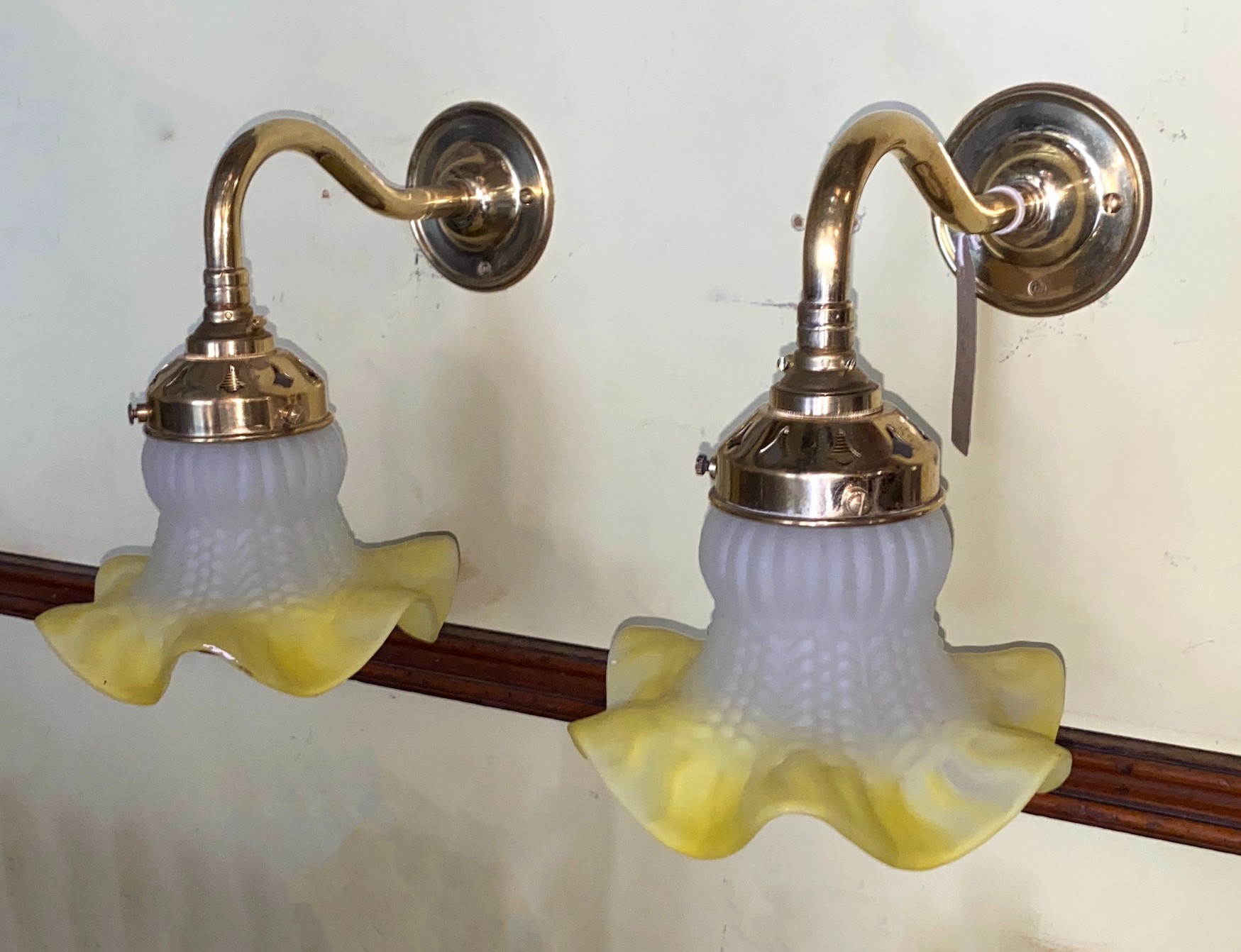 A pair of 1930s French lacquered brass wall lights with yellow tinted quilted and frosted glass