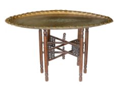 An unusually large early 20th century Indian brass oval tray top table with folding wooden