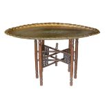 An unusually large early 20th century Indian brass oval tray top table with folding wooden