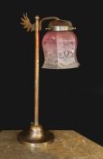 An Edwardian style bronze metal desk lamp with angel wing motif and cranberry tinted etched glass