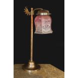 An Edwardian style bronze metal desk lamp with angel wing motif and cranberry tinted etched glass