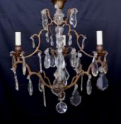 An early 20th century French bronze and cut glass three light chandelier, hung with tear shaped