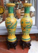 A pair of Chinese yellow glazed baluster vases decorated with bands of flowers and dragons, on