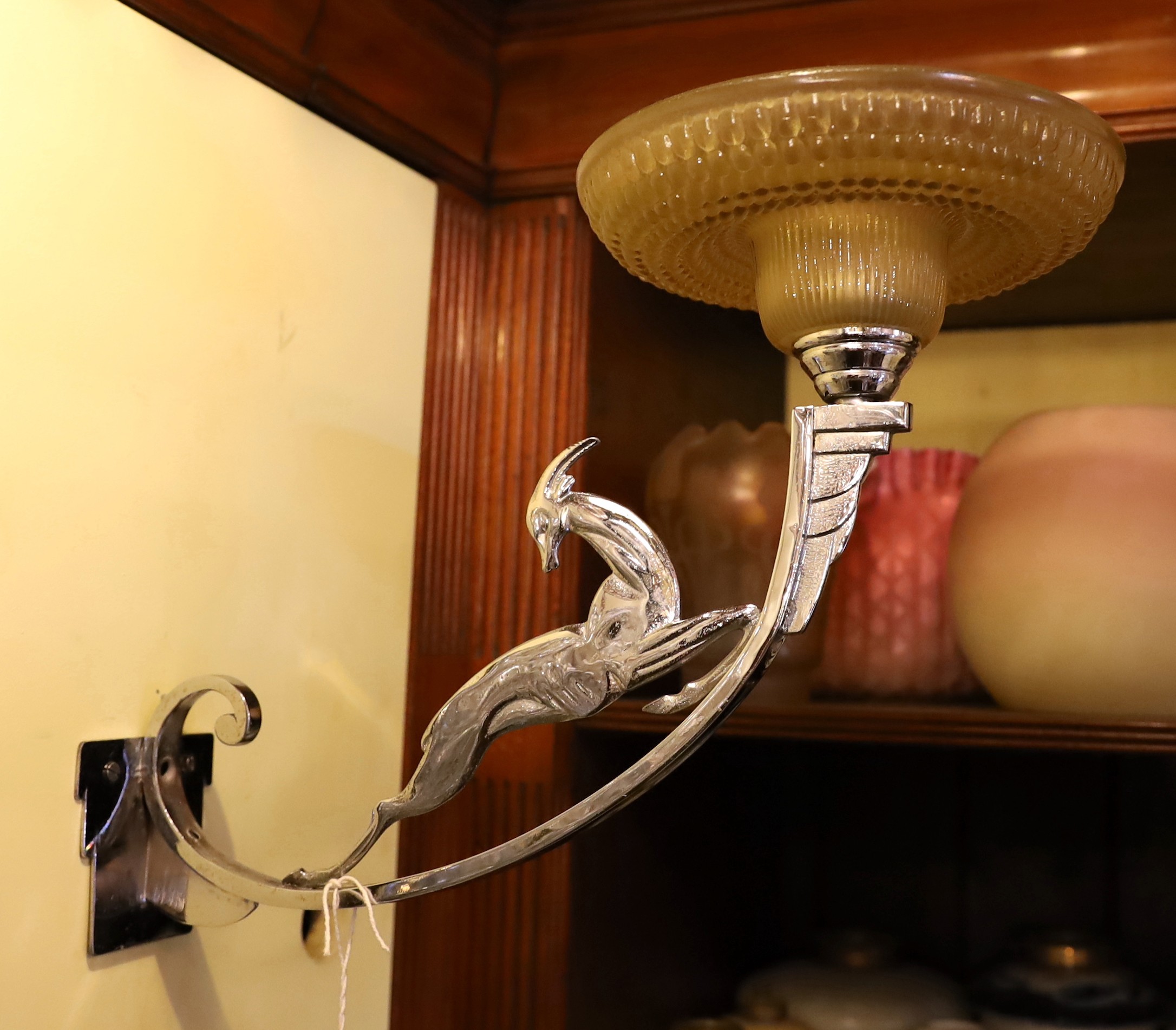 A French Art Deco nickel plated wall light with moulded glass shade and antelope stem, height