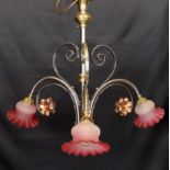 An English Arts & Crafts wrought iron brass and copper three light electrolier with pink tinted