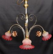 An English Arts & Crafts wrought iron brass and copper three light electrolier with pink tinted