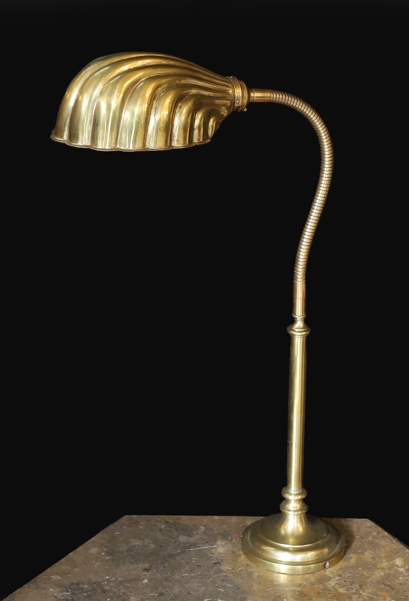 A 1930s English brass adjustable desk lamp, with flexible stem and scalloped shaped shade, height