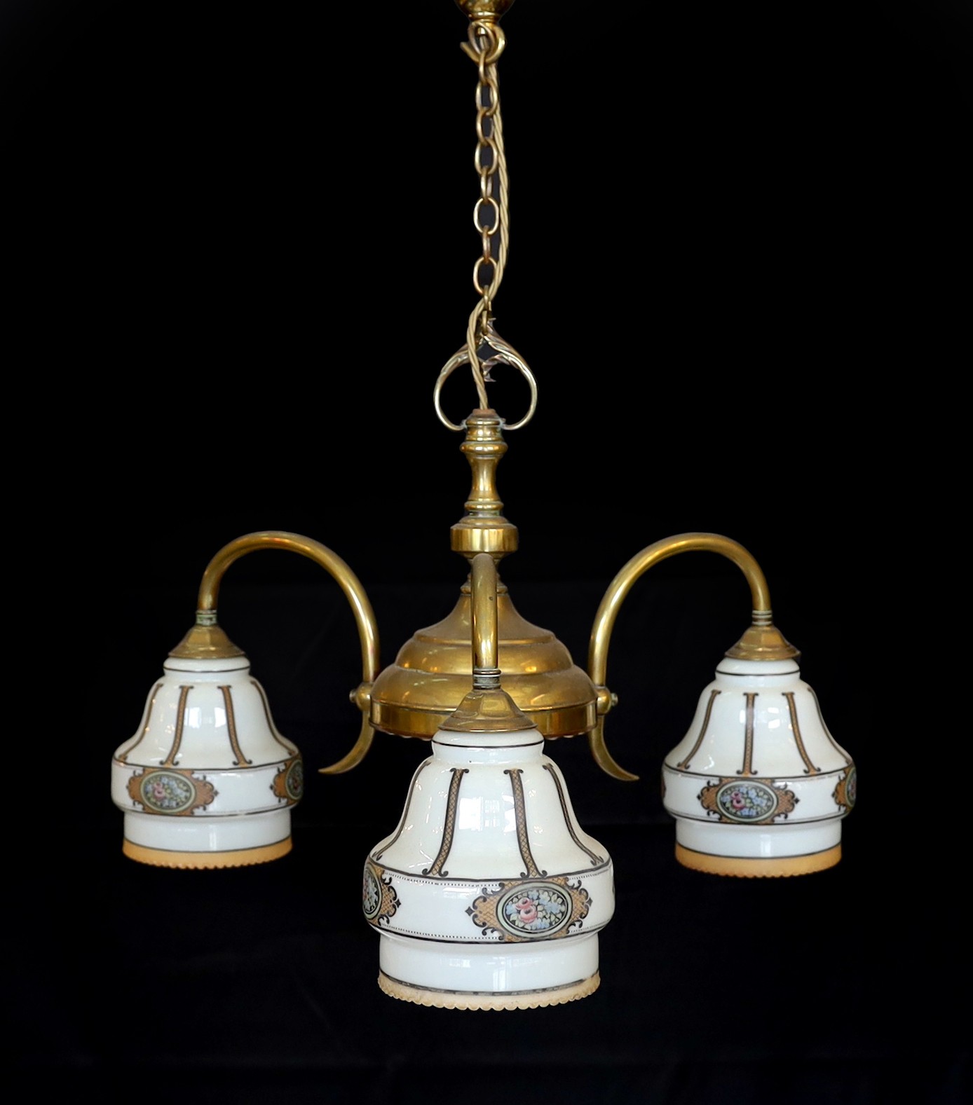 An early 20th century English lacquered brass light fitting with three stencilled opaque glass