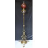 An Edwardian brass telescopic oil lamp standard, with later edged cranberry glass shade and duplex