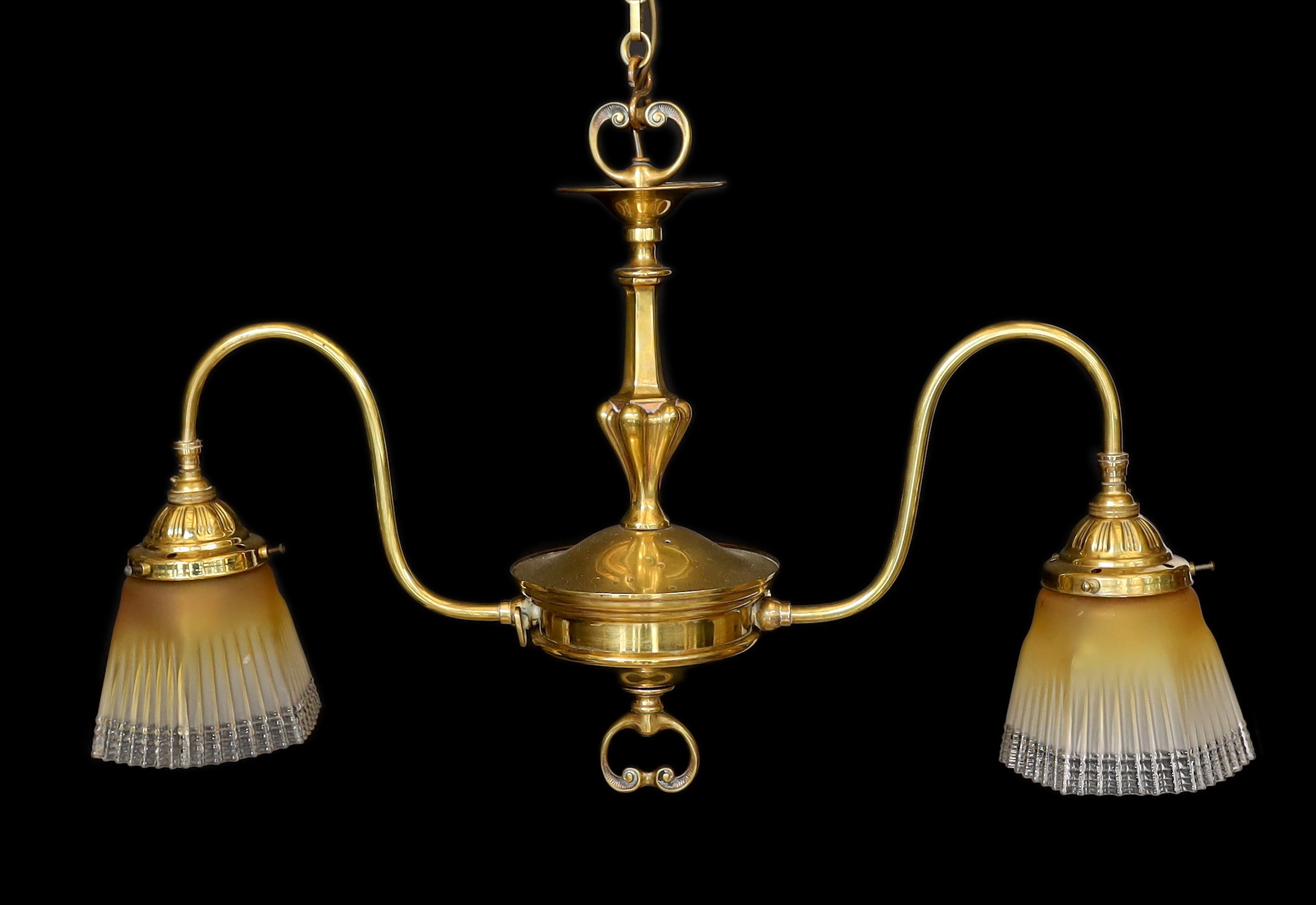 An early 20th century English brass twin branch light fitting with amber tinted tall glass shades