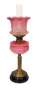 A late Victorian brass oil lamp with opaque pink glass reservoir, duplex mechanism, cranberry tinted