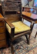 A 17th century style carved oak X-frame elbow chair with carved owl and figural motifs, width