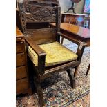 A 17th century style carved oak X-frame elbow chair with carved owl and figural motifs, width