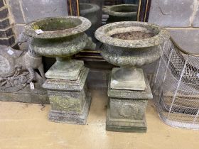 A pair of circular reconstituted stone campana garden urns on square plinths, one urn a.f., diameter