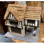 A contemporary doll's house modelled as a thatched house, width 70cm, height 60cm