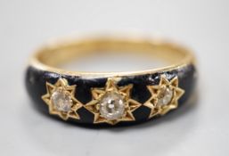 An Edwardian 18ct, black enamel and three stone gypsy set diamond mourning ring, size Q/R, gross