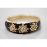 An Edwardian 18ct, black enamel and three stone gypsy set diamond mourning ring, size Q/R, gross