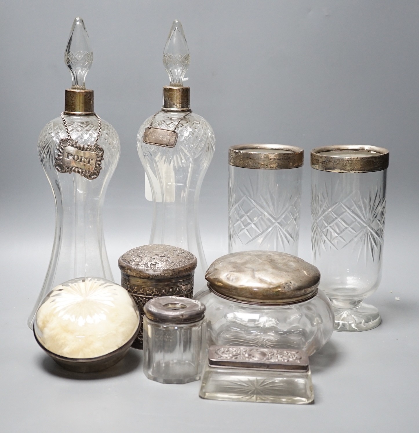 A collection of silver mounted glass items, including a pair of waisted decanters with two silver