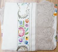 An ecru coloured embroidered tablecloth with crochet edge
