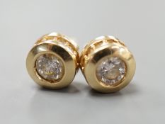 A modern pair of 14k yellow metal and single stone diamond set ear studs, with diamond chip setting,