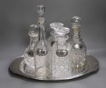 A silver plated oval tray, five assorted cut glass decanters and five assorted silver wine labels.