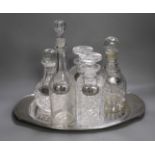 A silver plated oval tray, five assorted cut glass decanters and five assorted silver wine labels.