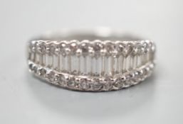 A modern white metal, graduated baguette cut diamond set half hoop ring, with diamond chip