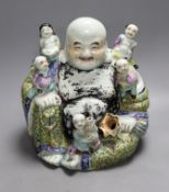 An early 20th century enamelled porcelain figure group of a seated Budai and children, 27.5cm high