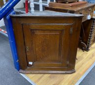 A small George III oak wall hanging corner cupboard, with hinged panelled door and shelved interior,