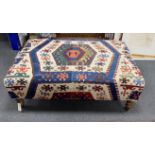 A large rectangular coffee table / footstool with antique kelim upholstery on stained turned beech