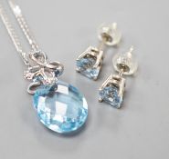A modern 14k white metal, facetted pear cut blue topaz and diamond chip set pendant, 19mm, on a