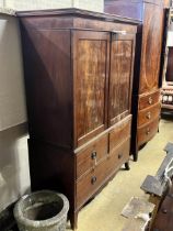 A George III mahogany linen press converted to a hanging wardrobe with part dummy drawer front,