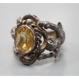 A 1960's silver and oval cut citrine set ring, the shank modelled and twin cupids, size O, gross