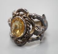A 1960's silver and oval cut citrine set ring, the shank modelled and twin cupids, size O, gross