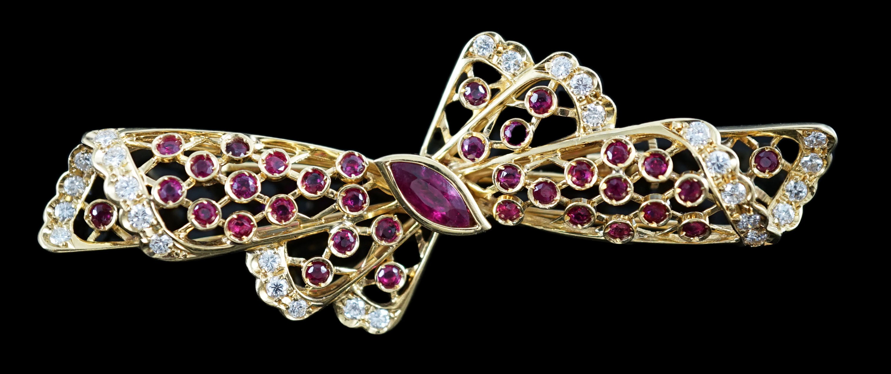 A mid to late 20th century pierced 18ct gold, ruby and diamond set ribbon bow brooch, with central