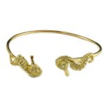 A modern gold and diamond chip set open work bangle, each terminal modelled as a seahorse with