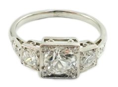 A platinum and millegrain set three stone diamond ring, with diamond set shoulders, the central