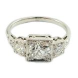 A platinum and millegrain set three stone diamond ring, with diamond set shoulders, the central