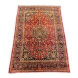 A Kashan claret ground carpet, woven with a central flowerhead medallion with palmettes and