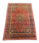 A Kashan claret ground carpet, woven with a central flowerhead medallion with palmettes and