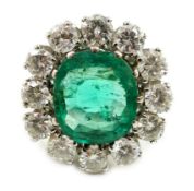 An impressive platinum, emerald and diamond set oval cluster dress ring, the emerald measuring