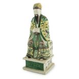 A Chinese enamelled biscuit figure of a seated court official, Kangxi period, wearing dragon