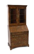 An early 18th century feather banded walnut bureau bookcase, with moulded cornice and two glazed