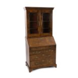 An early 18th century feather banded walnut bureau bookcase, with moulded cornice and two glazed