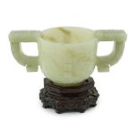 A Chinese archaistic celadon jade two handled cup, 17th century, carved in relief with archaistic