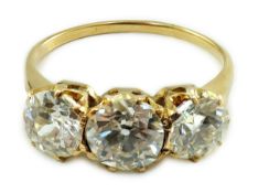 A gold and three stone diamond ring, with three round cut stones, the central stone weighing