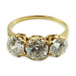 A gold and three stone diamond ring, with three round cut stones, the central stone weighing