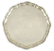 A George V shaped circular silver salver by Viners Ltd, with wavy border and engraved initials, on