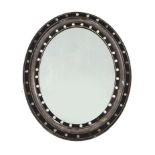 A 19th century Irish oval wall mirror, the ebonised and silvered frame applied faceted and